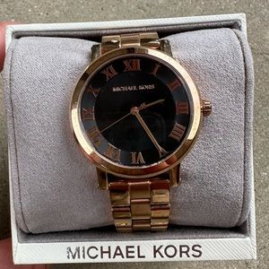 Rose gold Michael Kors watch with black face.